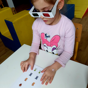 Dziewczynka ma kolorowe okulary i pokazuje zwierzątka.