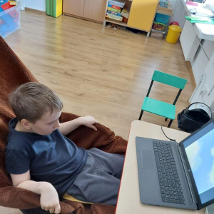 Chłopiec ogląda film edukacyjny na laptopie.