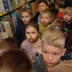 Dzieci zwiedzają bibliotekę i przechodzą między regałami