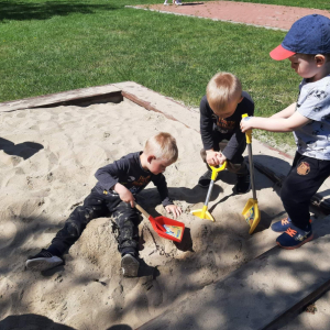 Trzech chłopców  bawi się w piaskownicy
