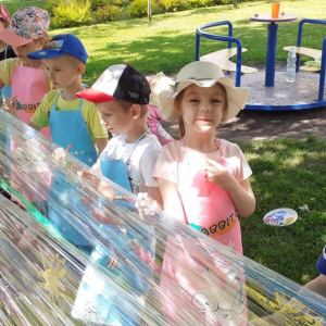 Dzieci bawią się super malując farbami na placu przedszkolnym.