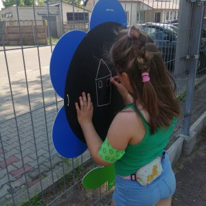 Dziewczynka maluje kredą po tablicy.