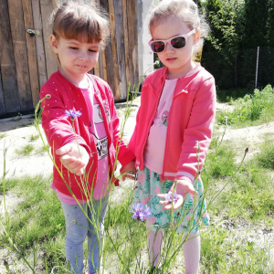 Dziewczynki trzymają kwiatki.