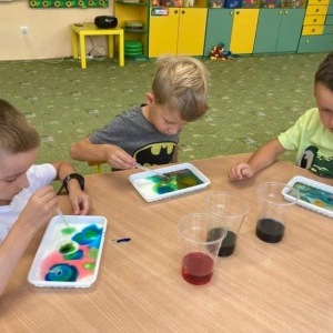 Dzieci malują kolorowymi barwnikami na mleku