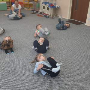 Dzieci wykonują ćwiczenie gimnastyczne pt. "Kołyska"t