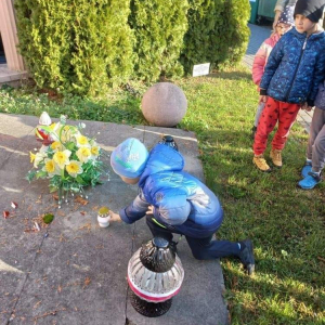 Chłopiec stawia znicz na pomniku