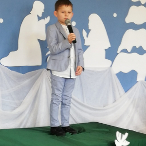 Chłopiec stoi na scenie i śpiewa.