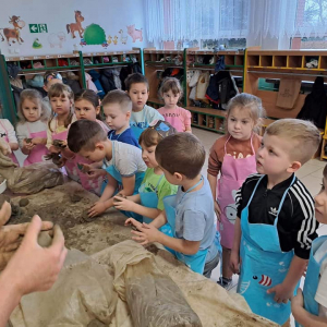 Dzieci z grupy Krasnoludki z uwagą słuchają o glinie i jej właściwościach.