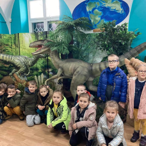  Dzieci stoją na tle dinozaurów