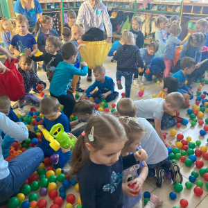 Dzieci za pomocą chwytaków zbierają kolorowe piłki do worka