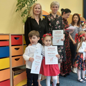 Dzieci z Paniami stoją i trzymają dyplomy w rękach