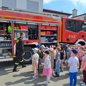Dzieci stoją przed wozem strażackim a Pan Strażak pokazuje sprzęt 