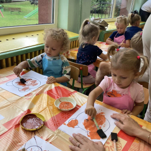 Dzieci malują misia farbami.
