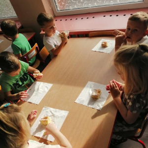 Dzieci siedzą przy stoliku i jedzą ciasto