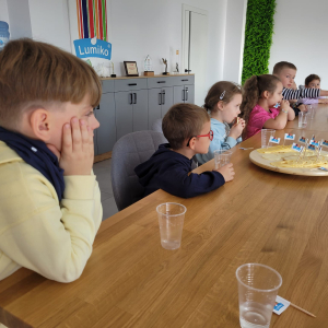 Dzieci siedzą przy stole i jedzą ser