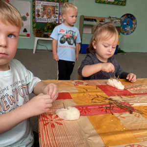 Dzieci siedzą przy stoliku i lepią jeżyka z masy solnej