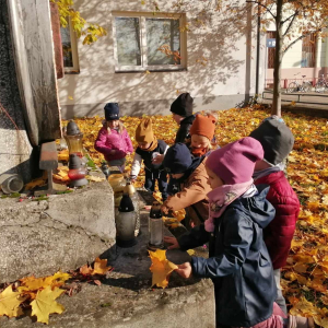 Dzieci zapalają znicz i stawiają przy pomniku