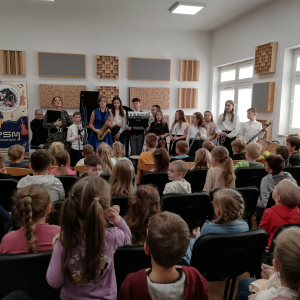 Dzieci siedzą i słuchają występu dzieci ze szkoły muzycznej