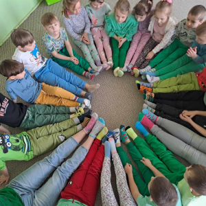 Dzieci z kolorowymi skarpetkami siedzą na dywanie 