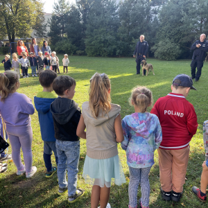 dzieci, policjanci i Panie stoją na trawie 