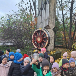 Dzieci stoja przed pomnikiem Kolejarza