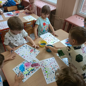 Dzieci malują na kartce kolorowe kropki palcami