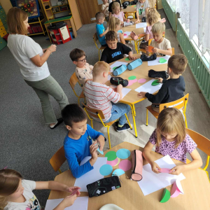 Dzieci przy stoliku wykonują pracę plastyczną
