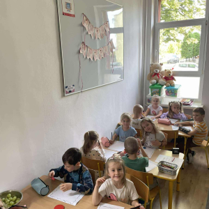 Dzieci siedzą przy stoliku i wykonują pracę plastyczną