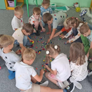 Dzieci zbierają z dywanu kolorowe kuleczki