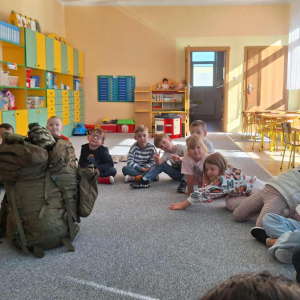 Dzieci siedzą w kole i słuchają opwieści żołnierza