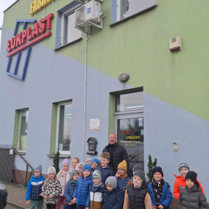 Dzieci stoja przed fabryka i pozują do wspólnego zdjęcia