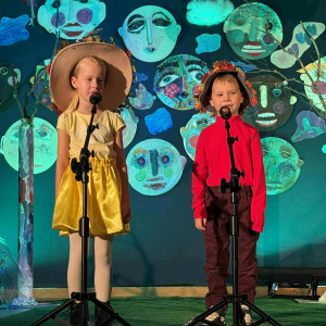 Dziewczynka i chłopiec recytują wiersz na scenie