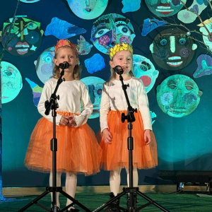Dwie dziewczynki recytują wiersz na scenie.