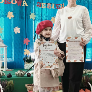 Pani Dyrektor stoi z dziewczynką, która trzyma dyplom.