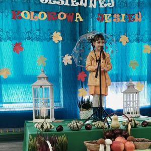 Dziewczynka stoi na scenie i śpiewa piosenkę.