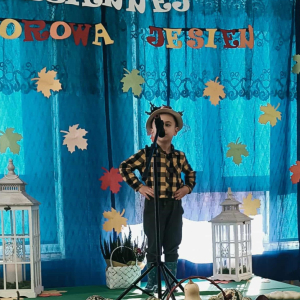 Chłopiec stoi na scenie i śpiewa piosenkę.