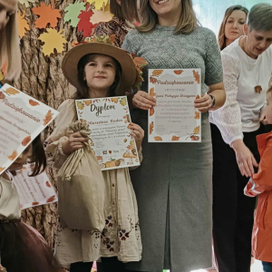 Pani nauczycielka i dziewczynka, obie trzymają dyplomy.