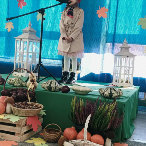 Dziewczynka stoi na scenie i śpiewa piosenke.