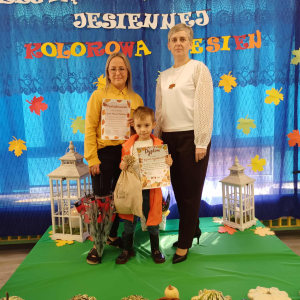 Chłopiec reprezentujący nasze przedszkole stoi na scenie wraz z Panią Dyrektor i swoim opiekunem.