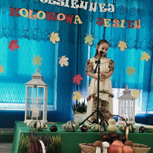 Dziewczynka stoi na scenie i śpiewa piosenkę.