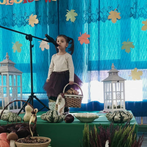 Dziewczynka stoi na scenie i śpiewa piosenkę.