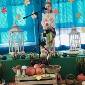 Dziewczynka stoi na scenie i śpiewa piosenkę.