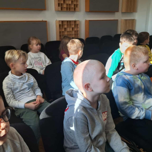 Dzieci siędzą na widowni i słuchają koncertu.