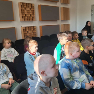 Dzieci siędzą na widowni i słuchają koncertu.