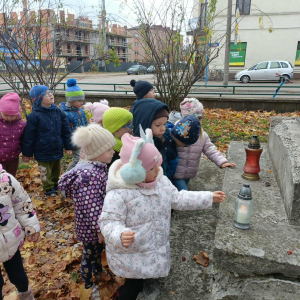 Dzieci stawiają znicz na pomniku Kolejarza
