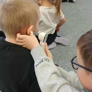 Chłopiec zagląda do uszu specjalnym urządzeniem.