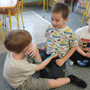 Chłopiec bada kolegę za pomocą stetoskopu.