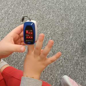 Chłopiec ogląda pulsoksymetr.