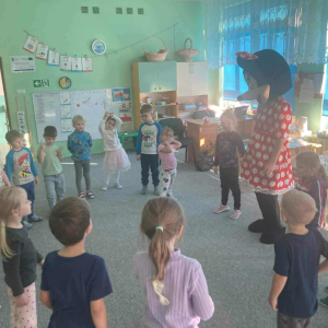 Dzieci tańczą w kole z Myszką Minnie.