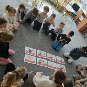 Dzieci siedzą na dywanie na środku leżą ilustracje